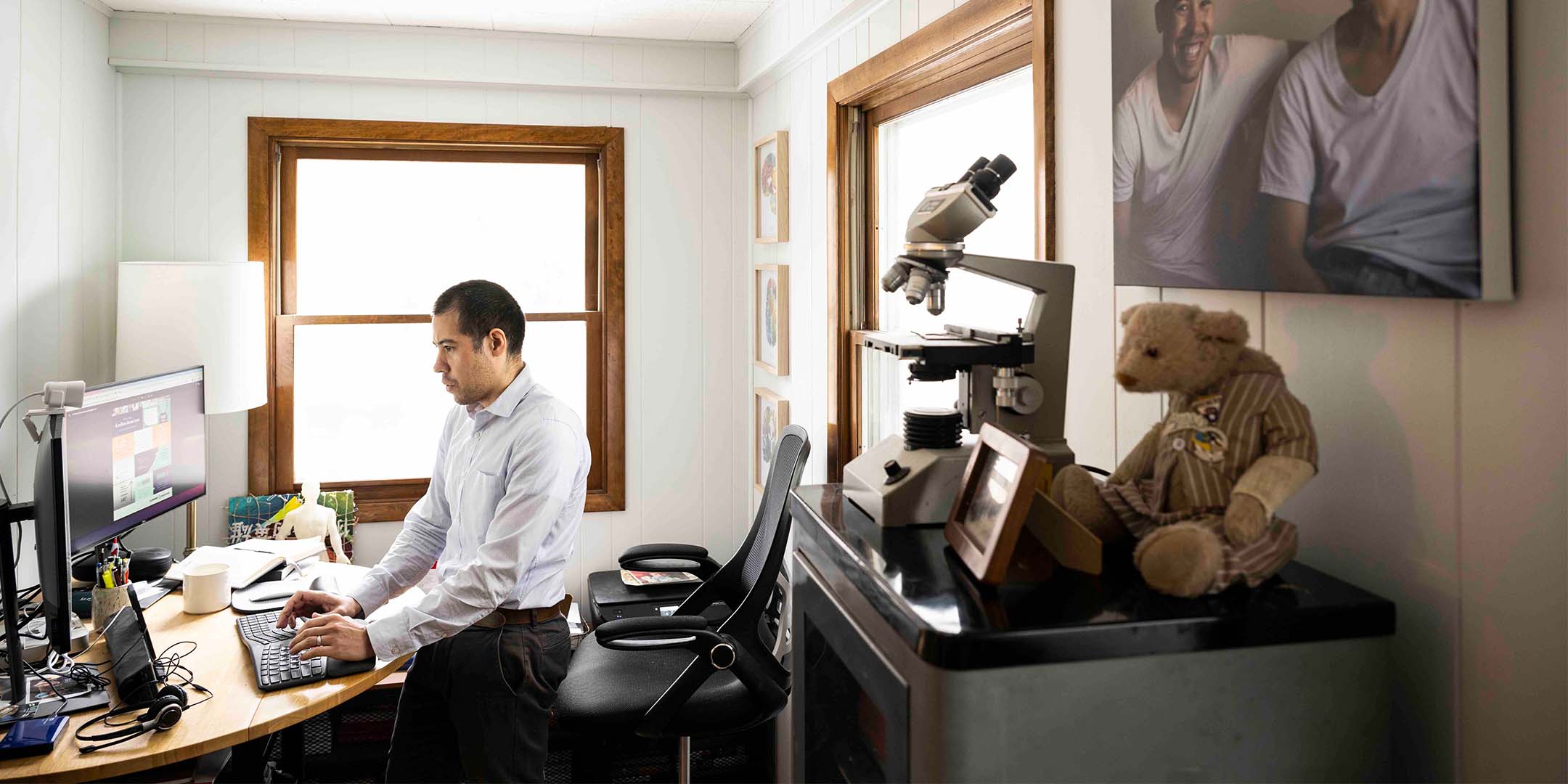 Nate Chin works at a computer in his home office, with keepsakes from his father nearby.