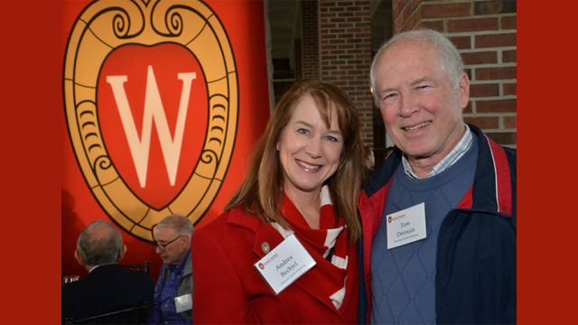 Two people posing by a Wisconsin banner