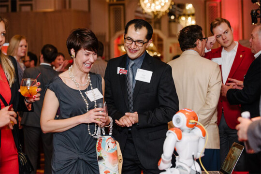 Attendees examining a robot at a booth