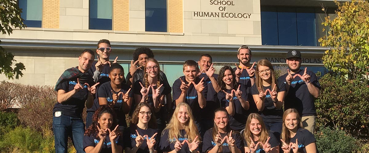 Student in front of the School of Human Ecology
